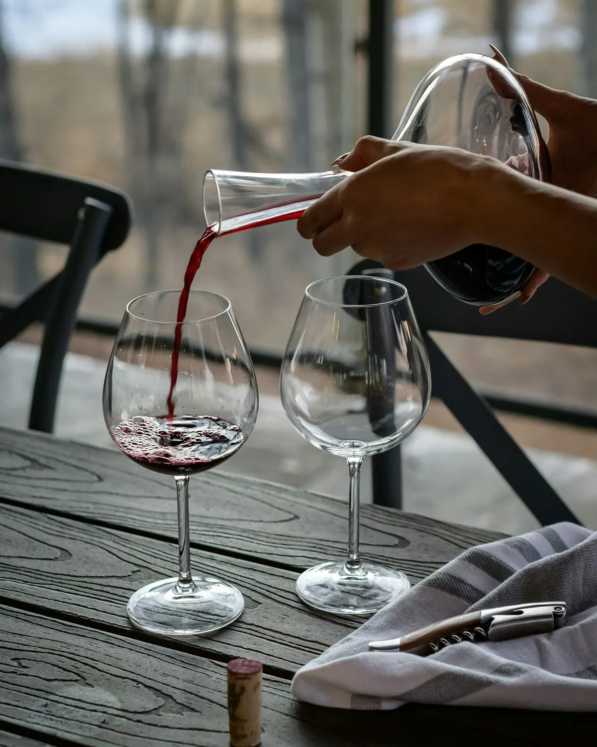 Czerwone wino przelewane z karafki do kieliszka na tarasie